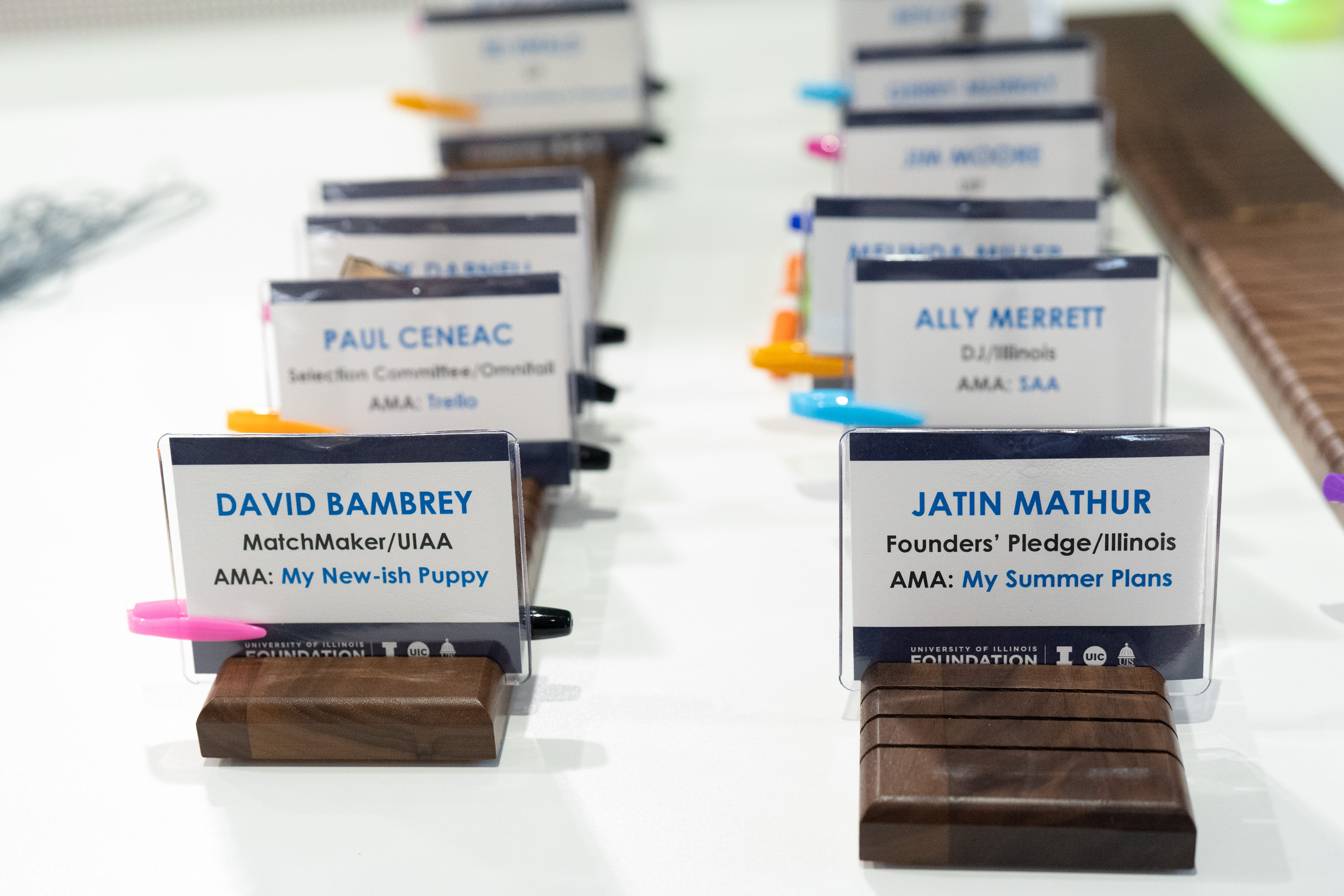 Photo of name badges at check-in desk with Ask Me About prompt and dry erase markers